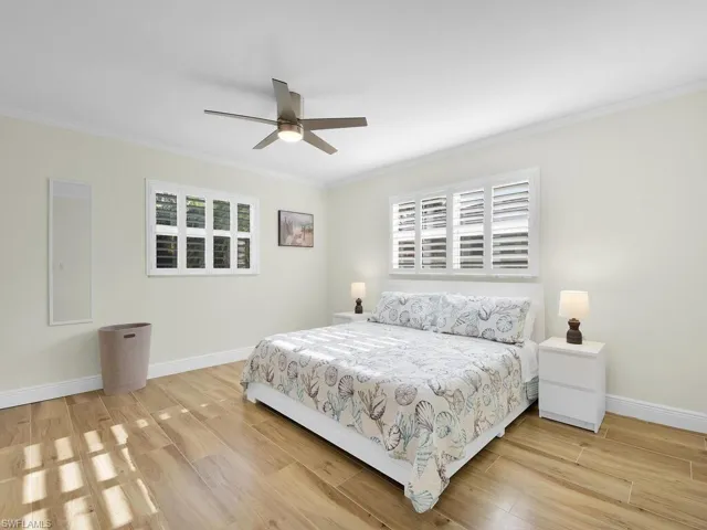 Bedroom with ornamental molding, light wood finished floors, and a ceiling fan
