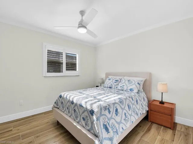 Bedroom featuring wood tiled floors, crown molding, and ceiling fan