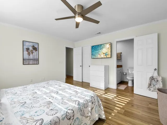 Bedroom with crown molding, wood finished floors, ensuite bathroom, and ceiling fan