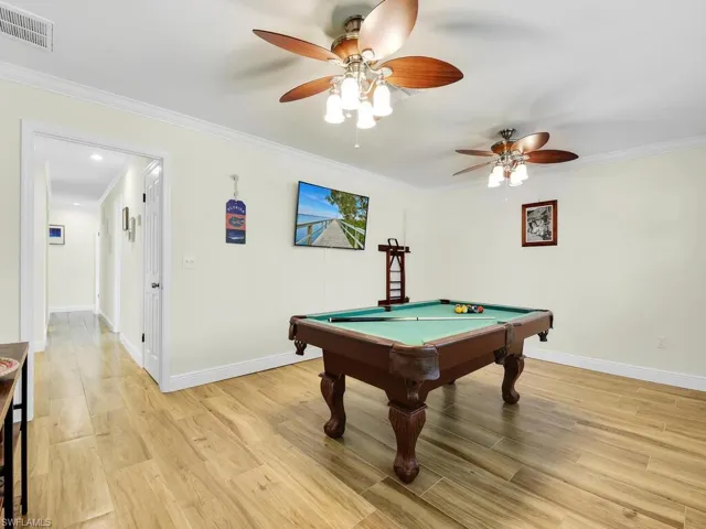 Recreation room featuring ornamental molding, billiards, light wood-type flooring, and a ceiling fan