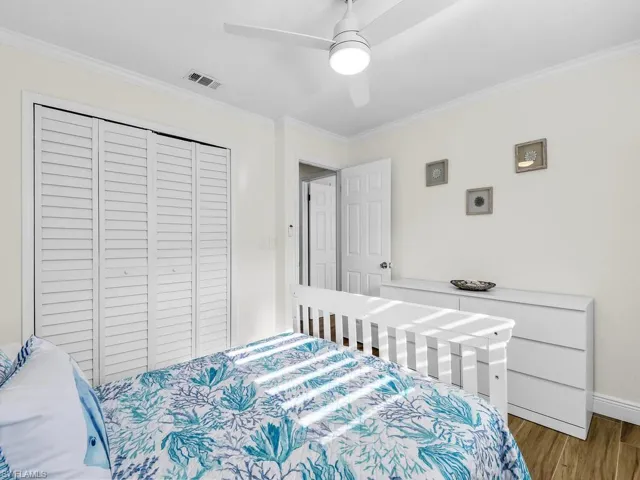 Bedroom featuring crown molding, a closet, a ceiling fan, and wood finished floors
