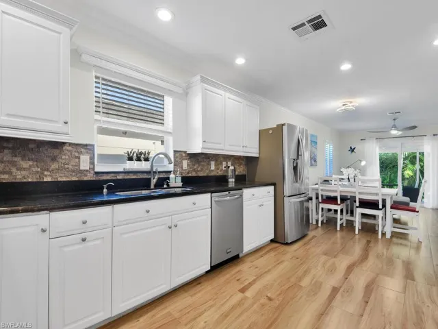 Kitchen featuring white cabinets, stainless steel appliances, ceiling fan, light wood finished floors, and recessed lighting
