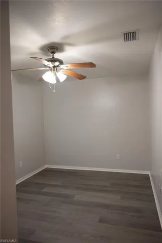 Unfurnished room featuring dark wood-type flooring and ceiling fan