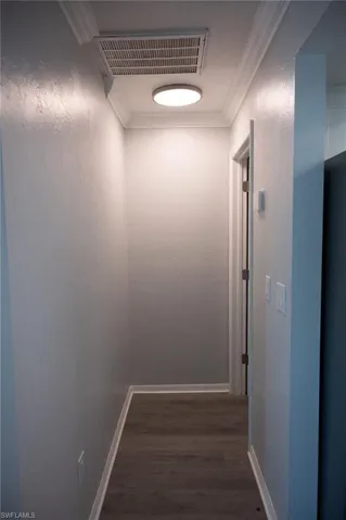 Corridor with crown molding and dark wood finished floors