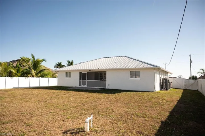 Back of property featuring stucco siding, a fenced backyard, a patio, and a metal roof