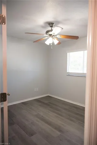 Empty room featuring dark wood finished floors and a ceiling fan