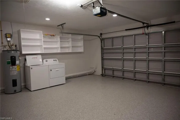 Garage featuring water heater, washer and clothes dryer, a garage door opener, and recessed lighting