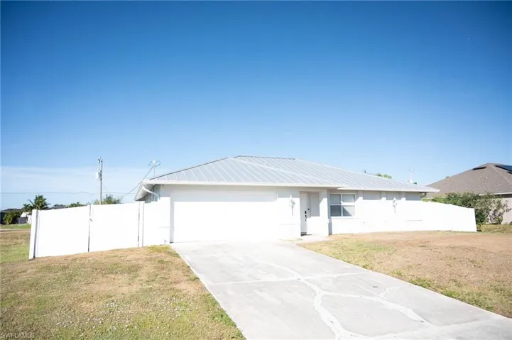 Single story home with a metal roof, concrete driveway, and a garage