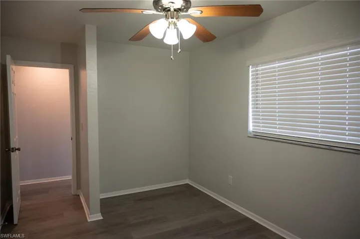 Empty room featuring ceiling fan and dark wood-style flooring