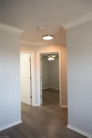 Corridor with crown molding and dark wood-style floors