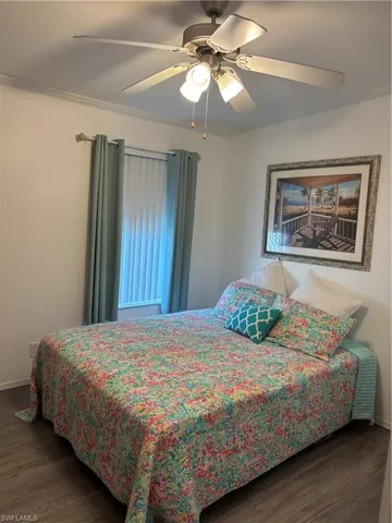 Bedroom with dark wood finished floors, a ceiling fan, and ornamental molding