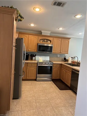 Kitchen with crown molding, electric range, stainless steel microwave, fridge, and light countertops