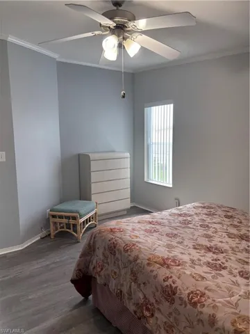 Bedroom with ornamental molding, dark wood-style flooring, and ceiling fan