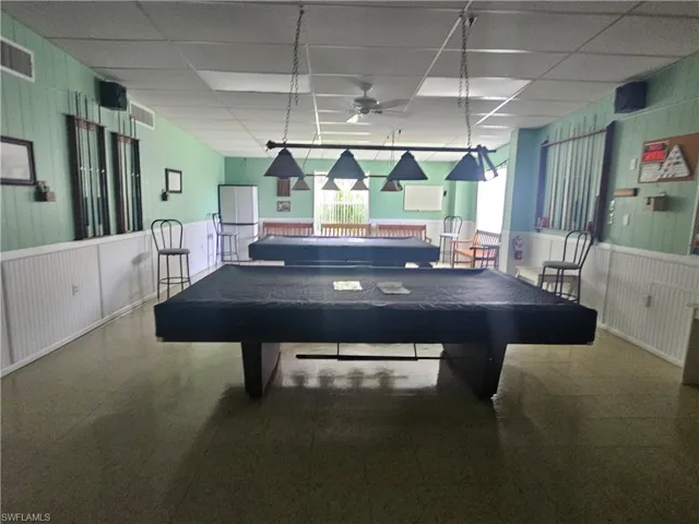 Recreation room with a drop ceiling, wainscoting, wooden walls, billiards table, and ceiling fan