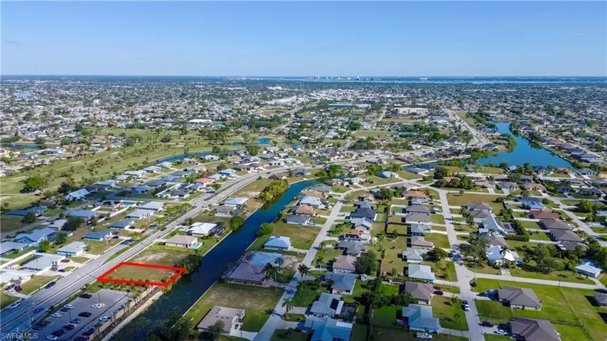 Aerial view of property and surrounding area with property parcel outlined, a nearby body of water, and nearby suburban area