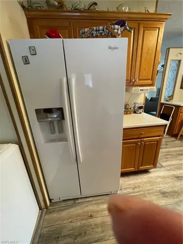 Kitchen featuring light wood-type flooring and white refrigerator with ice dispenser