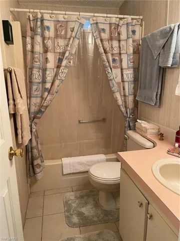 Full bathroom with tile patterned floors, vanity, shower / tub combo, and toilet