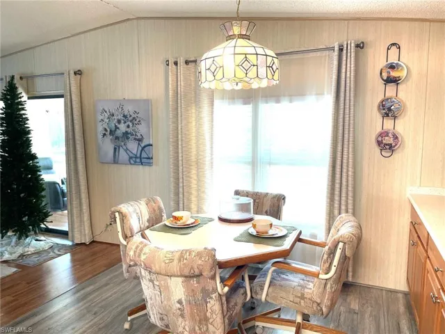 Dining area featuring healthy amount of natural light, dark wood finished floors, vaulted ceiling, and a textured ceiling