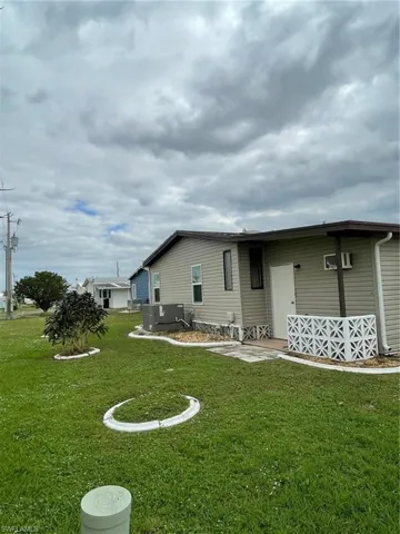 Rear view of house featuring a lawn and central air condition unit