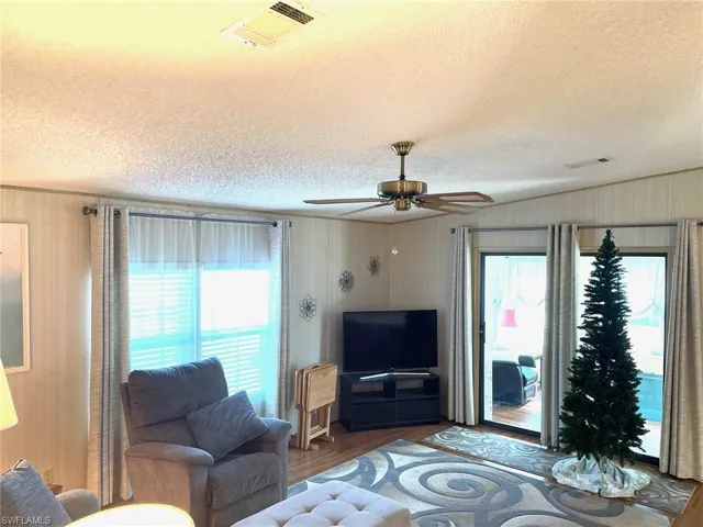 Living room with a textured ceiling, wood finished floors, and a ceiling fan