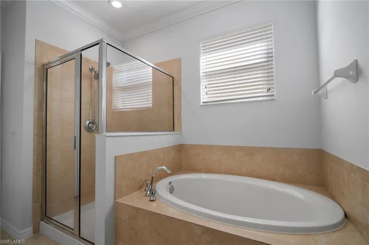 Bathroom with a garden tub, a shower stall, and crown molding