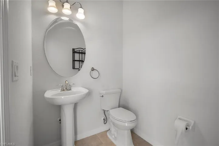 Bathroom with tile patterned flooring, baseboards, a sink, and toilet
