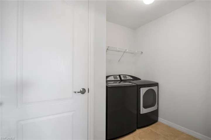 Washroom with laundry area, light tile patterned floors, baseboards, and independent washer and dryer