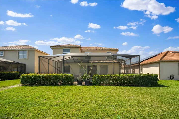 Back of house with a yard, a lanai, and a tiled roof