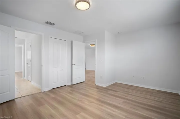 Unfurnished bedroom with light wood-type flooring, visible vents, and baseboards