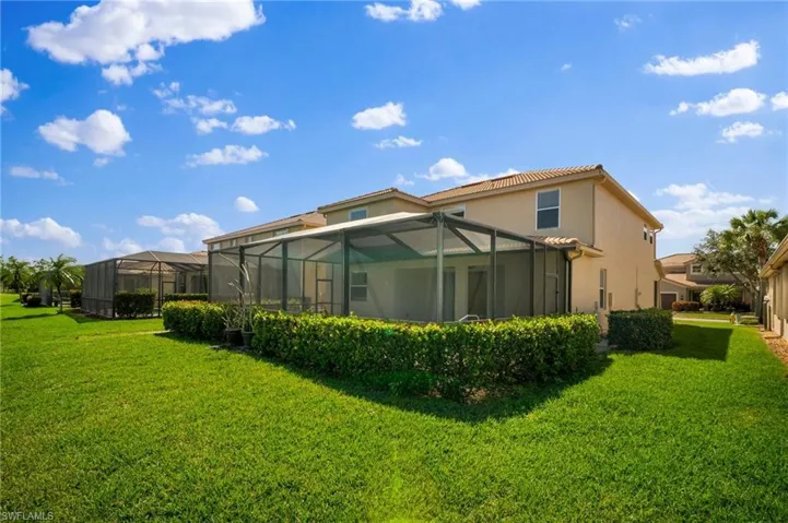 Rear view of property with a lanai, a lawn, and stucco siding