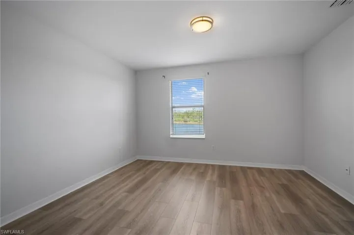 Empty room featuring visible vents, baseboards, and wood finished floors