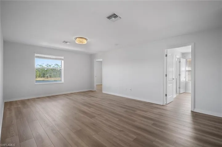 Spare room featuring wood finished floors, visible vents, and baseboards