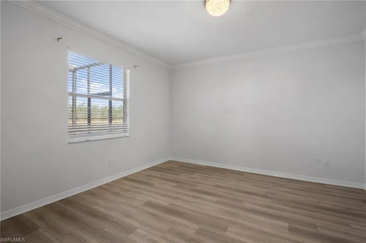 Spare room featuring ornamental molding, baseboards, and wood finished floors