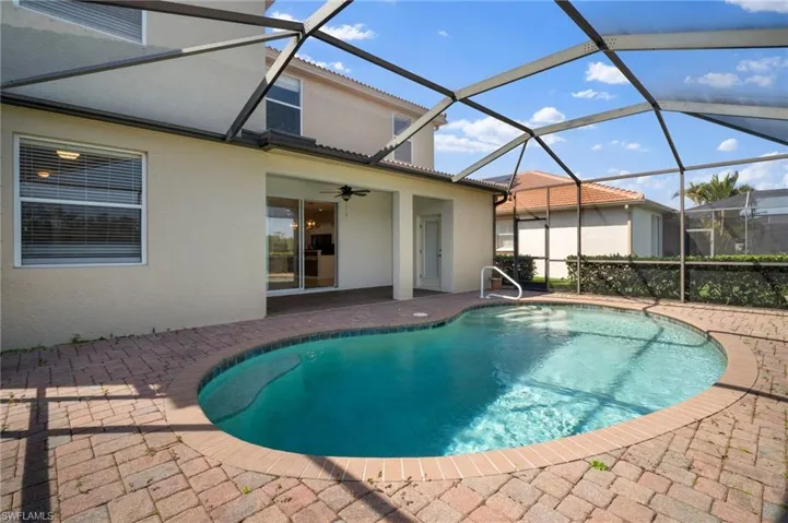 Pool featuring glass enclosure, a patio area, and a ceiling fan
