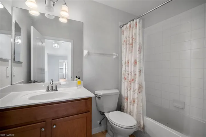 Full bathroom featuring toilet, shower / bath combination with curtain, and vanity