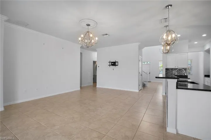 Kitchen featuring visible vents, dark countertops, an inviting chandelier, white cabinetry, and a sink