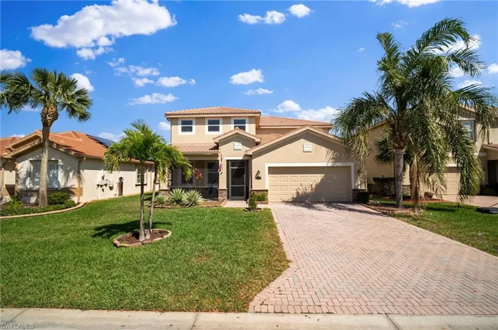 Mediterranean / spanish home featuring a garage, a tile roof, decorative driveway, a front lawn, and stucco siding