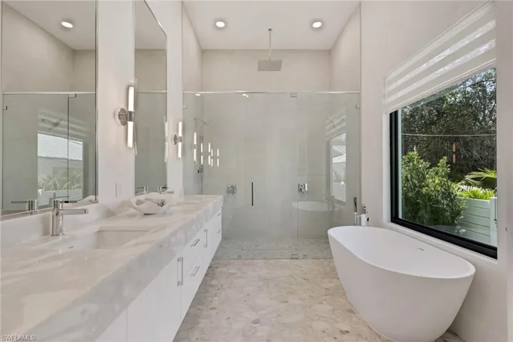 Full bath with a freestanding bath, a shower stall, double vanity, and recessed lighting