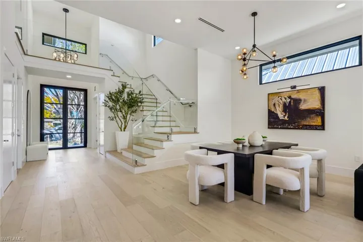Dining room featuring suspended lighting, a high ceiling, light wood-style floors, and plenty of natural light