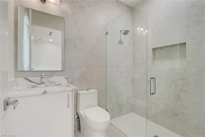 Bathroom featuring vanity, tile walls, and a marble finish shower