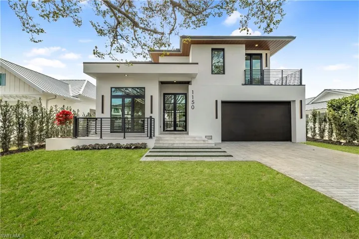 Back of property with stucco siding, an attached garage, a yard, decorative driveway, and a balcony