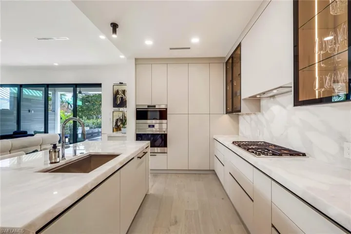 Kitchen with light wood finished floors, light stone counters, modern cabinets, and recessed lighting
