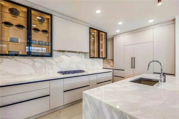 Kitchen with modern cabinets, light stone countertops, white cabinets, recessed lighting, and tasteful backsplash