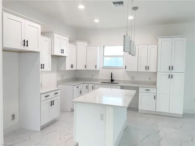 Kitchen featuring a kitchen island, sink, and white cabinets