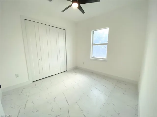 Unfurnished bedroom with ceiling fan and a closet