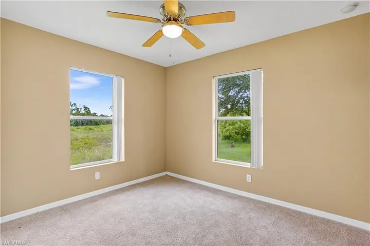 Carpeted spare room with ceiling fan and a wealth of natural light
