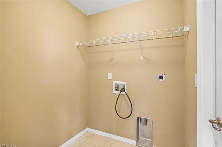 Laundry room with hookup for a washing machine, electric dryer hookup, and light tile floors
