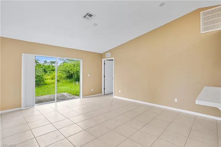 Unfurnished room featuring lofted ceiling and light tile floors