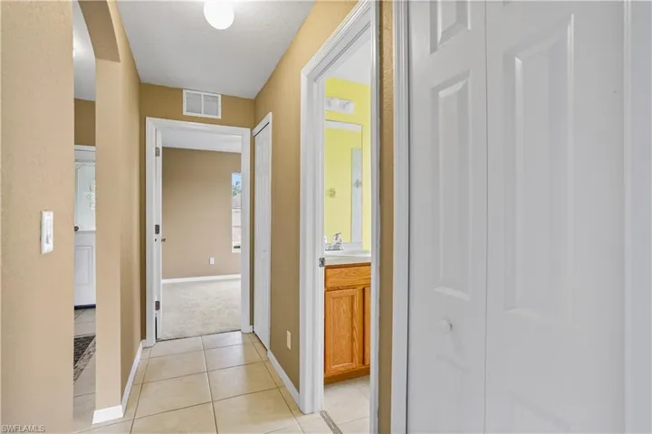 Hallway featuring sink, a textured ceiling, and light tile floors