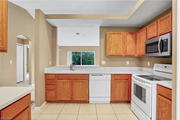 Kitchen featuring white appliances, sink, and light tile floors